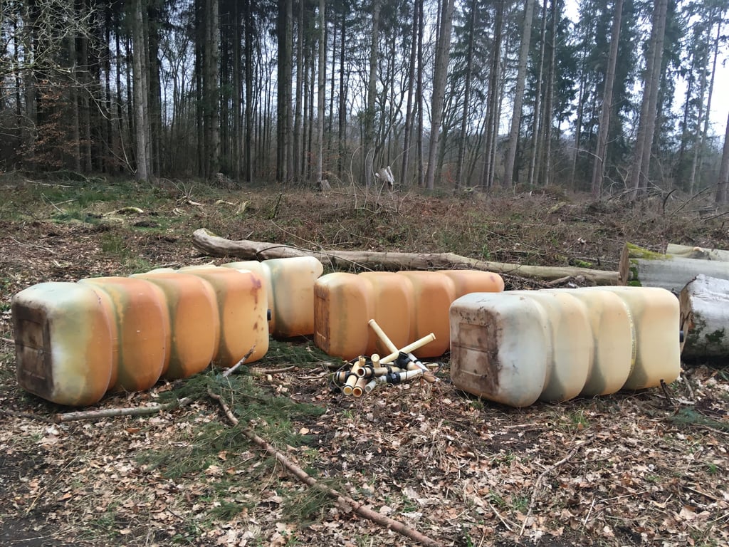 Unbekannte laden leere Tankbehälter im Wald ab